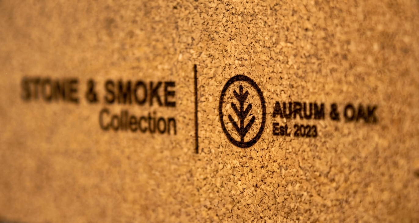 Close-up of a cork base engraved with Stone & Smoke Collection, the Aurum & Oak logo, and Est. 2023 — the branded underside of a handmade concrete object by Aurum & Oak.